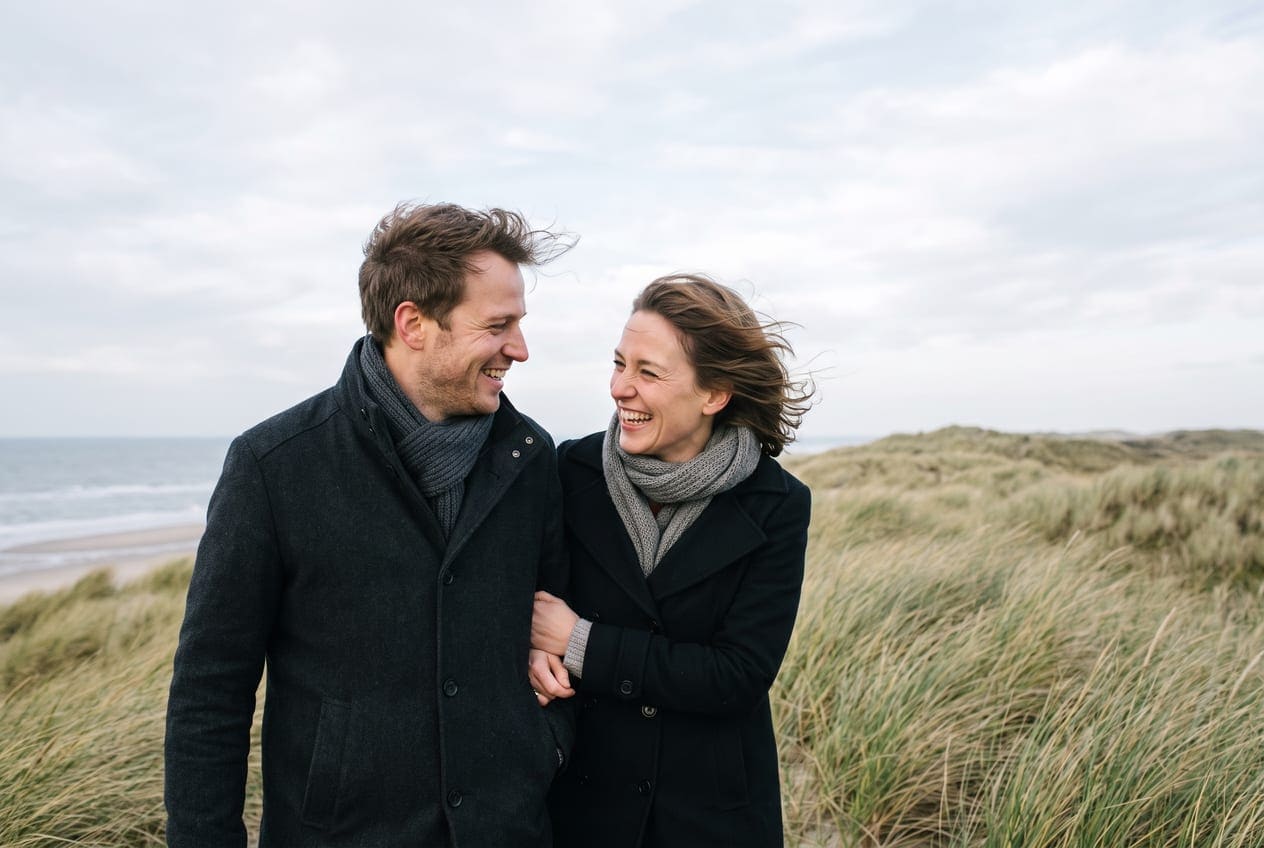 Stel wandelt in de herfst over een leeg Nederlands strand